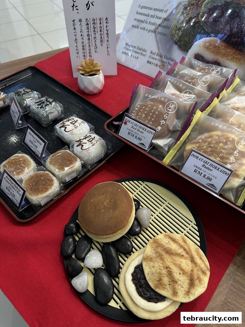 A display of Japanese sweets, including mochi and dorayaki, with price tags and descriptions.