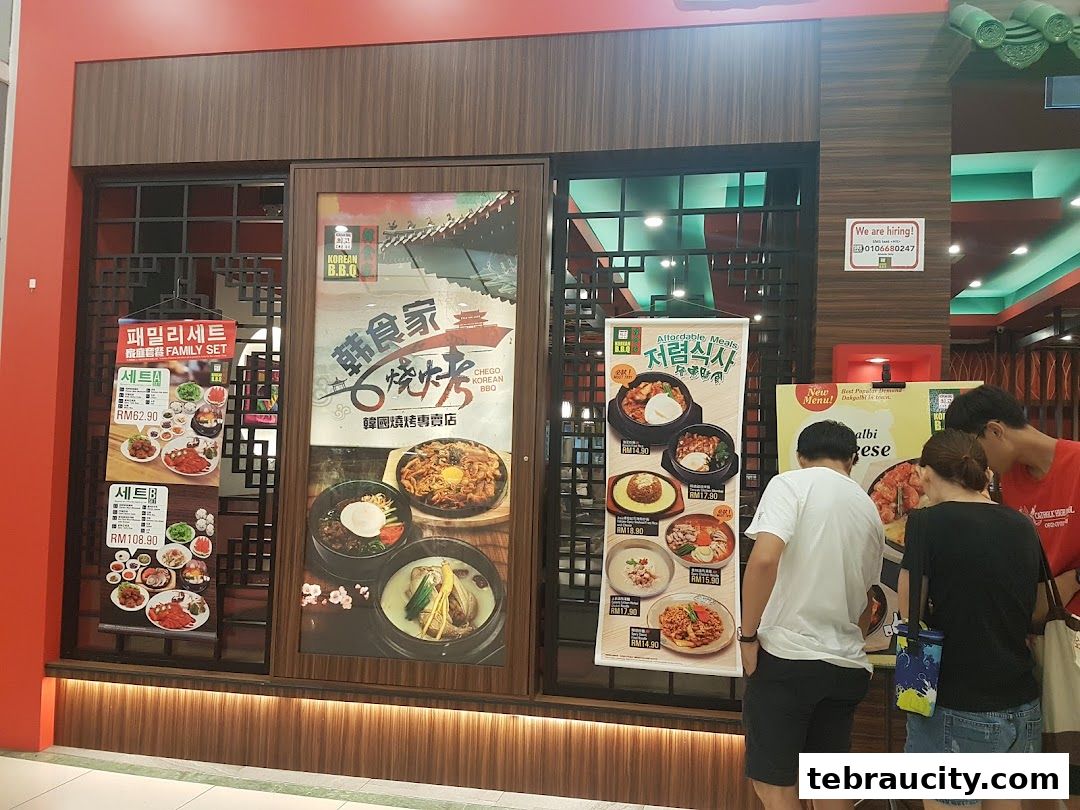 People looking at menus outside a Korean BBQ restaurant with various food displays.