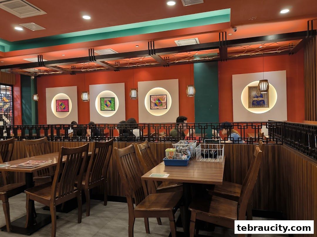 Interior view of a Korean BBQ restaurant with wooden tables, chairs, and vibrant orange walls.