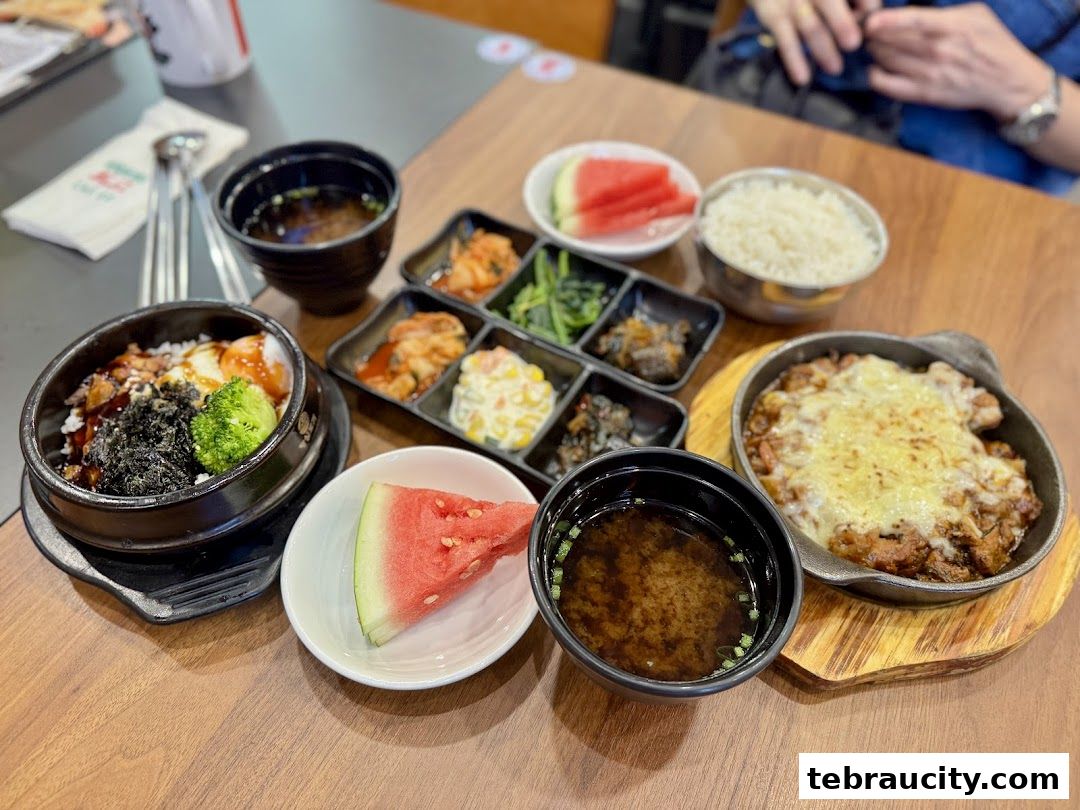 A table laden with Korean dishes, including bibimbap, cheese chicken, and various banchan.