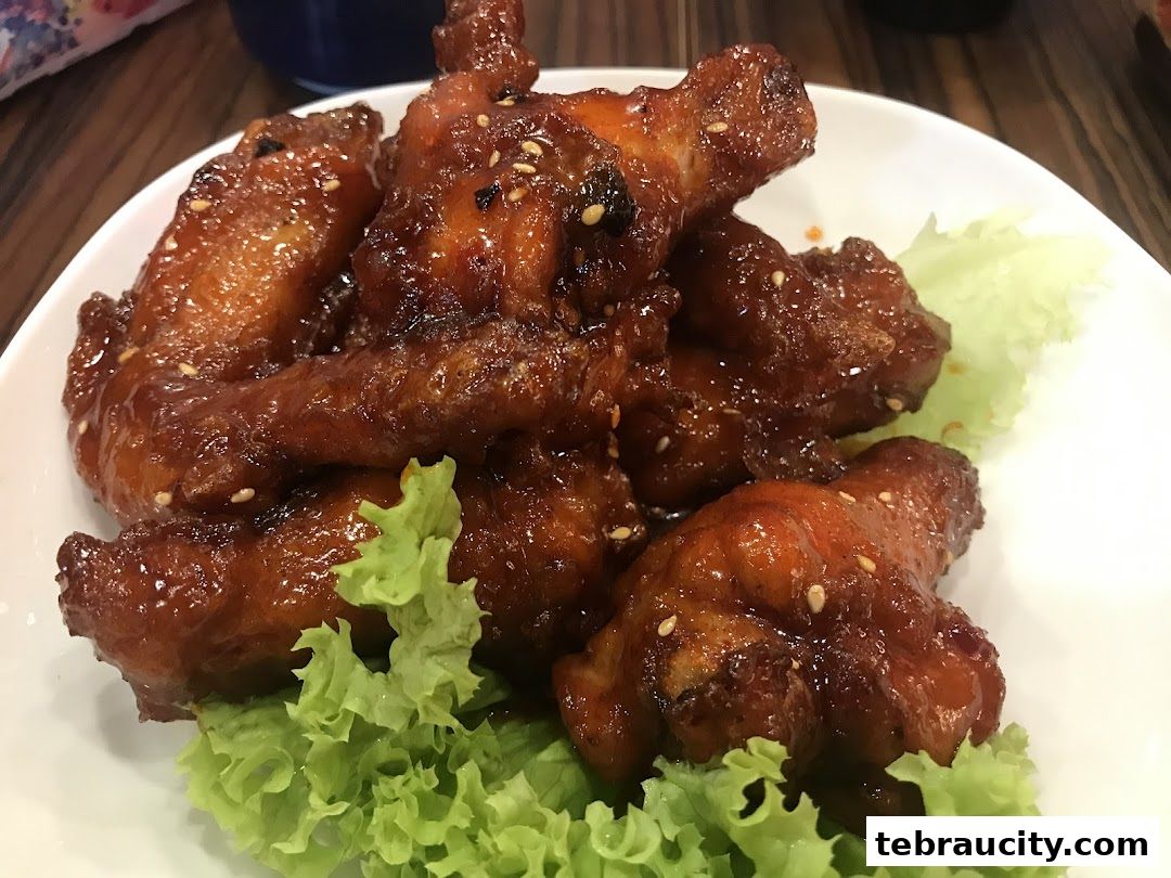 A plate of glistening Korean fried chicken wings with sesame seeds and lettuce.