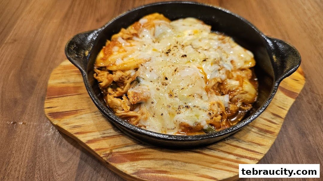 A close-up of a sizzling Korean dish with melted cheese in a cast-iron pan.