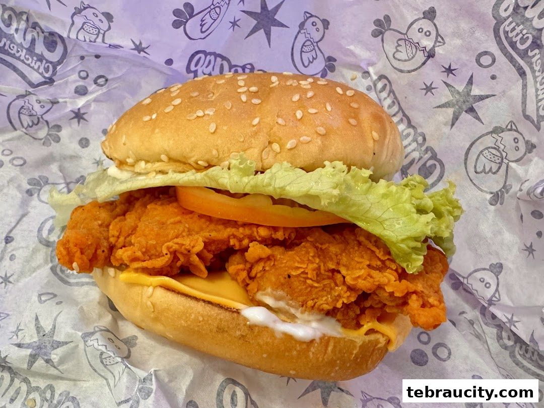 A close-up shot of a delicious fried chicken burger with lettuce, tomato, and cheese.