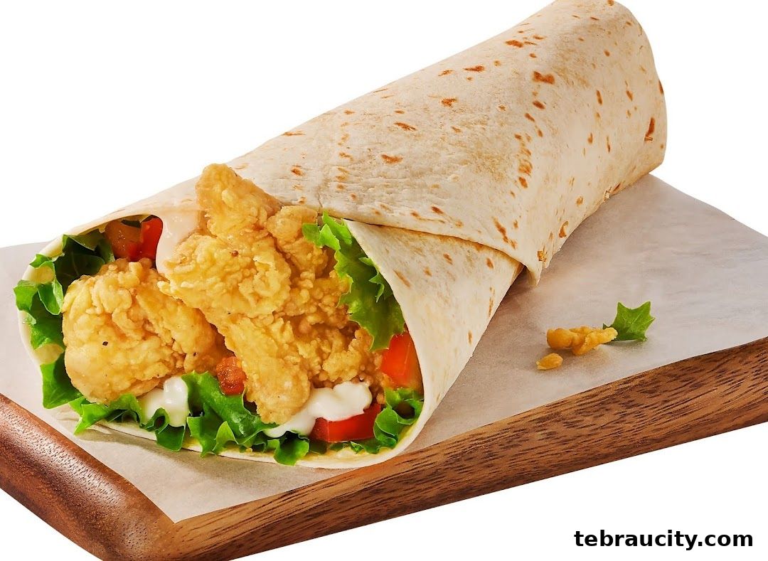 A delicious chicken wrap with fresh lettuce, tomatoes, and sauce on a wooden board.