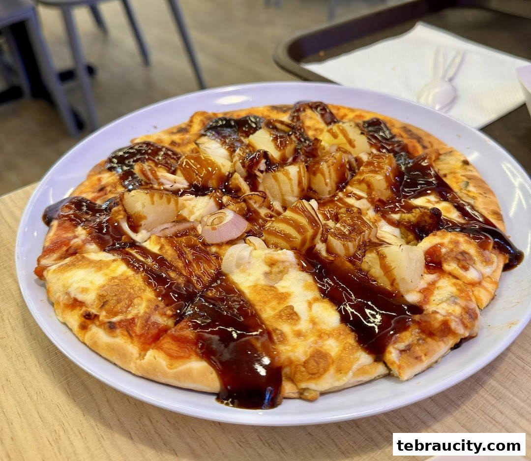 A close-up shot of a delicious pizza topped with pineapple, chicken, and a rich BBQ sauce.