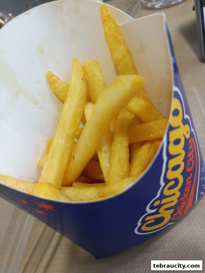 A close-up shot of golden French fries served in a branded blue container from Chicago Chicken City.