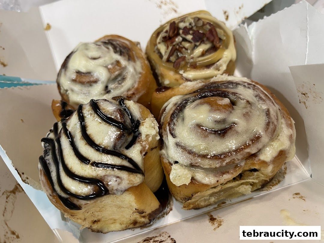 A box of four delicious Cinnabon cinnamon rolls with frosting and chocolate drizzle.