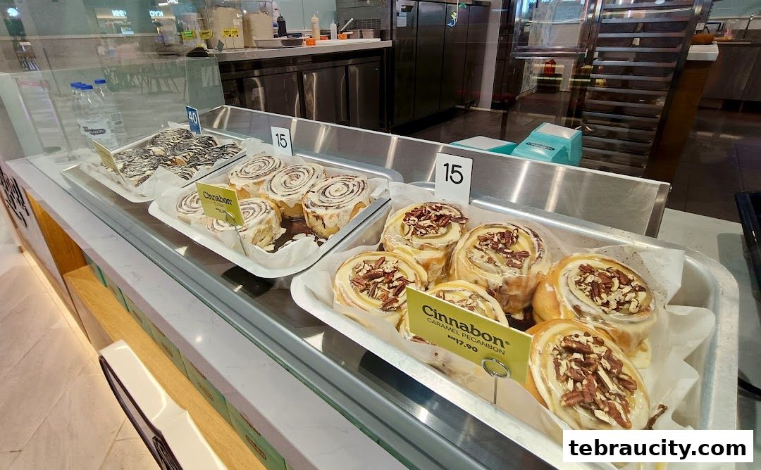 A display case filled with freshly baked Cinnabon cinnamon rolls, some topped with pecans.