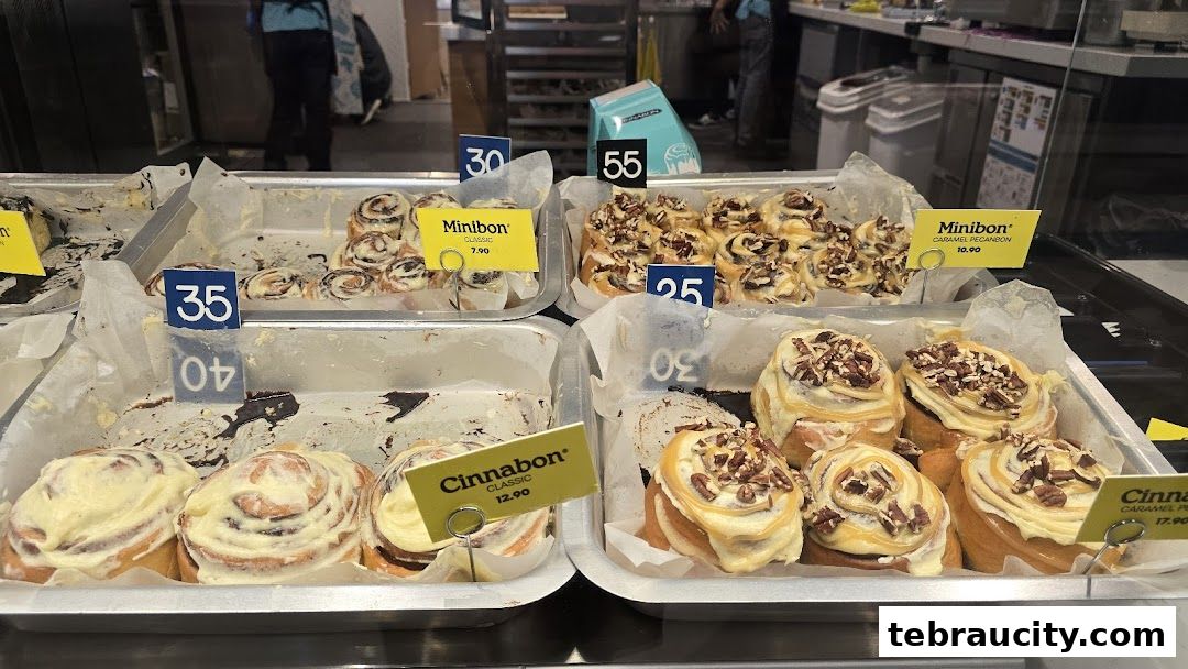 A display of freshly baked Cinnabon and Minibon cinnamon rolls with various toppings and prices.