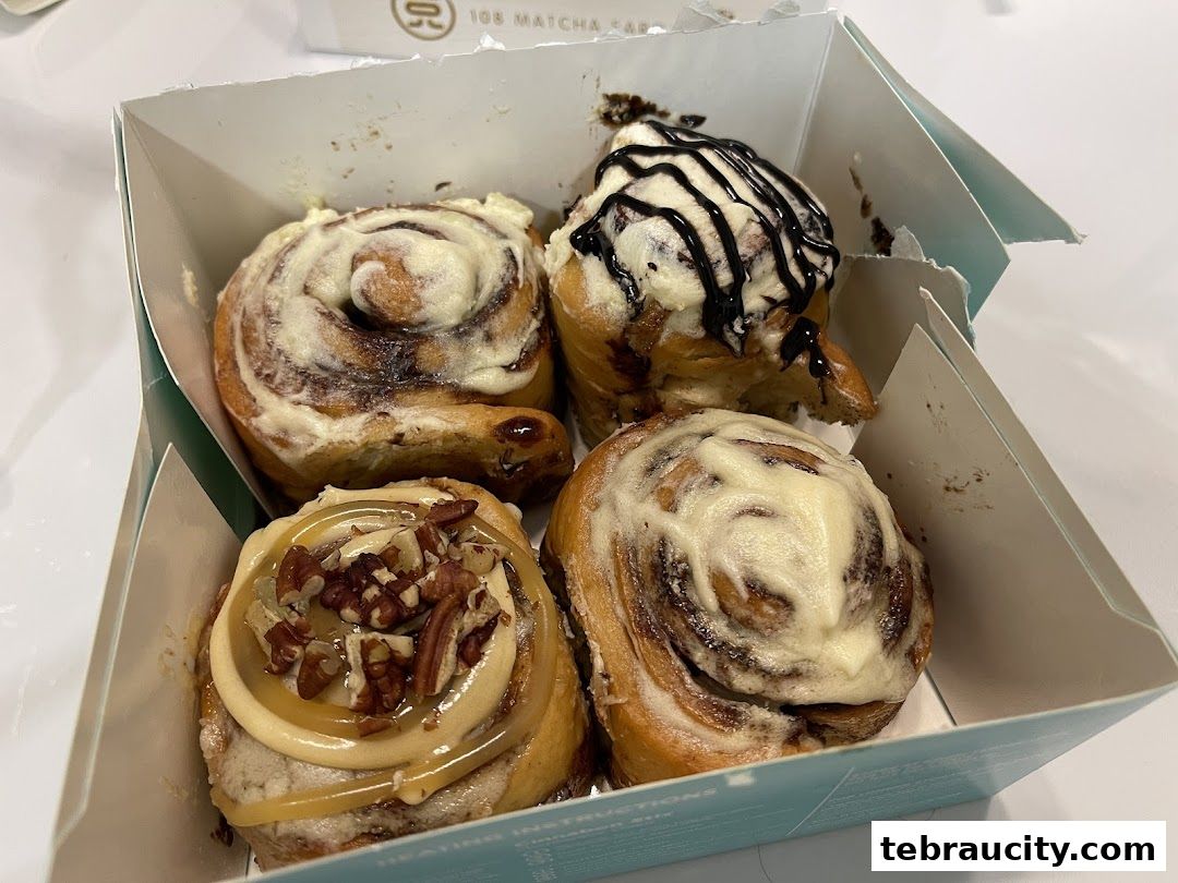 A box of four freshly baked Cinnabon cinnamon rolls with various toppings.