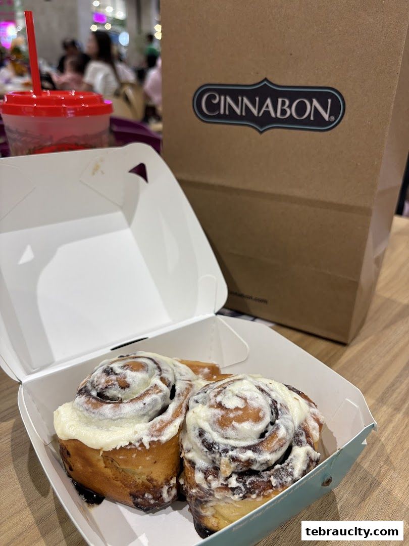 A box of Cinnabon cinnamon rolls with a Cinnabon bag and drink in the background.