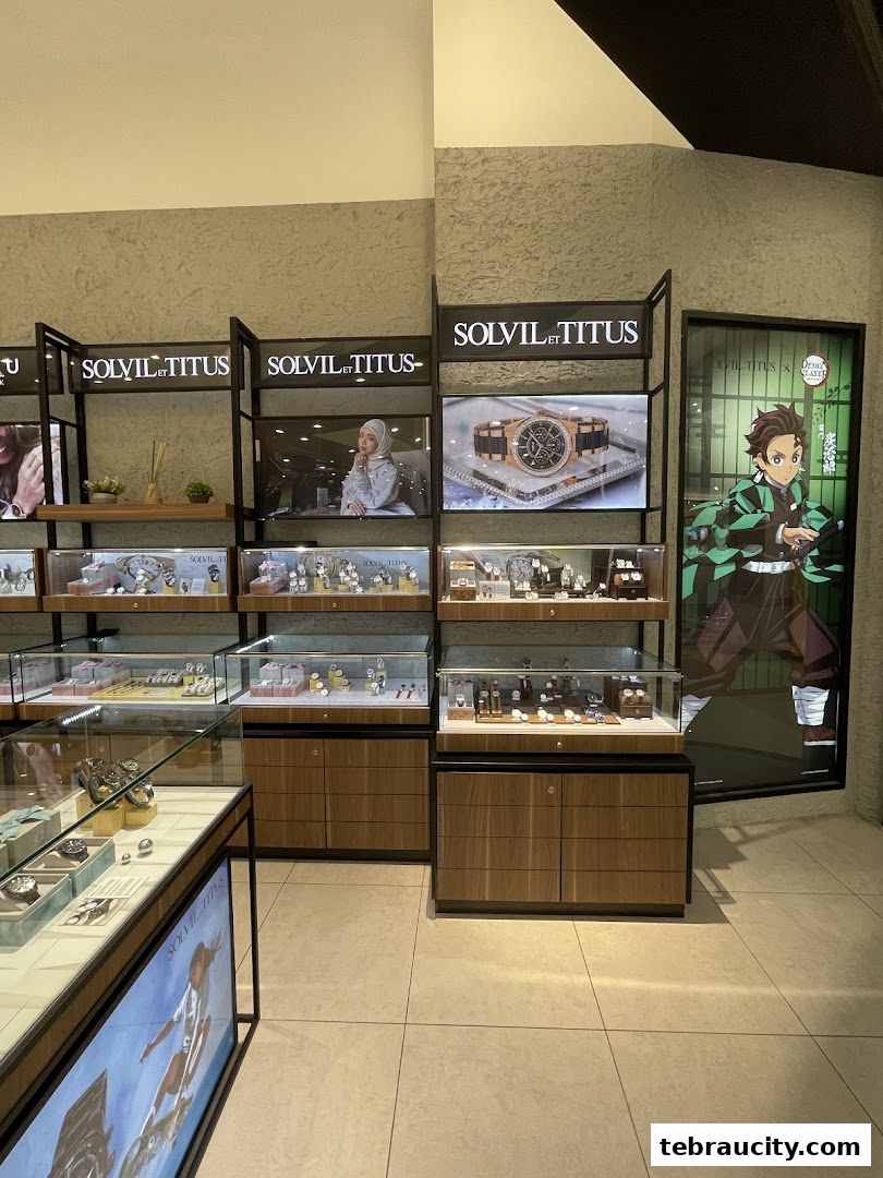 Interior view of a watch shop displaying various timepieces in glass cases and promotional posters.