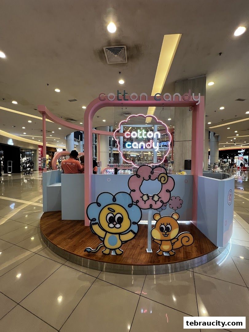 A colorful cotton candy stall with cartoon characters and neon signage in a shopping mall.
