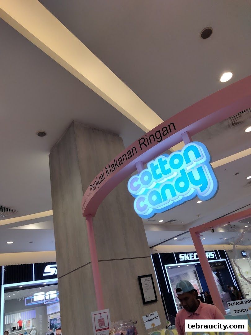 A shop front with a bright 'Cotton Candy' sign and a vendor preparing treats.