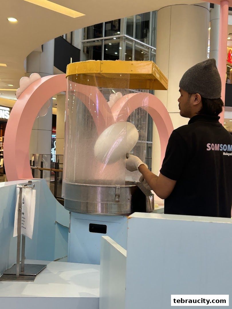 A vendor makes cotton candy at a colorful stall in a shopping mall.