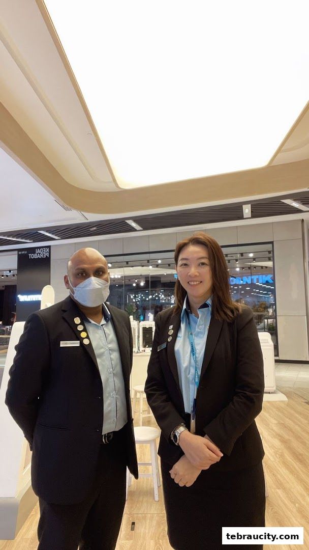 Two staff members, a man and a woman, stand in a brightly lit retail store.