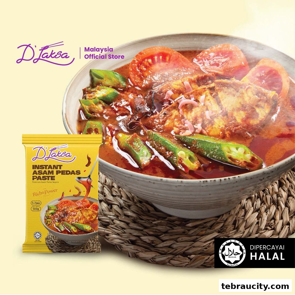 A bowl of Asam Pedas fish with okra and tomatoes, next to a packet of D'Laksa Instant Asam Pedas Paste.