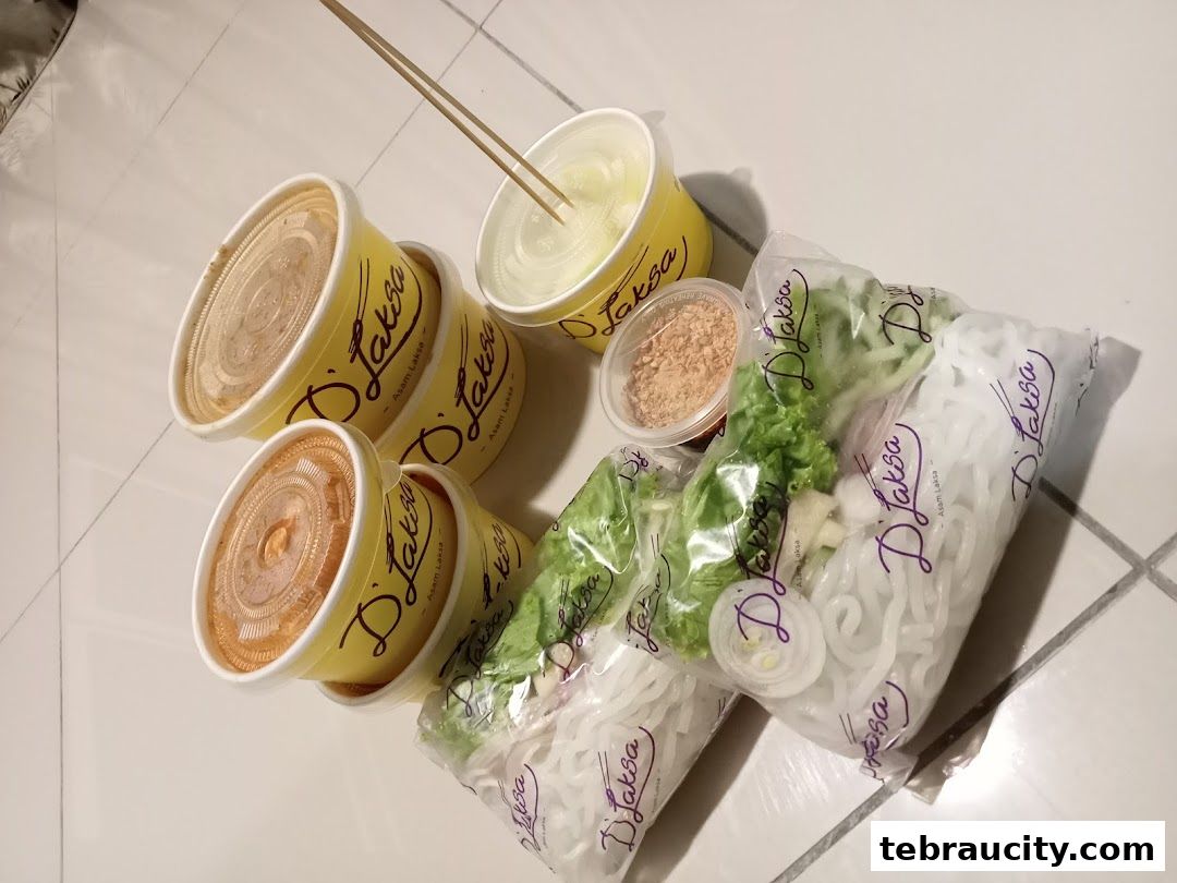 A collection of D'Laksa takeaway containers and ingredients, including noodles and vegetables.