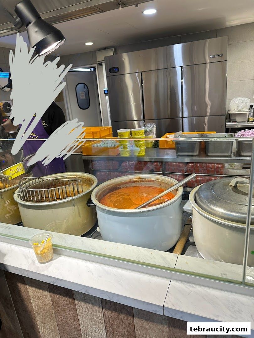 A food stall counter with large pots of curry and other ingredients, ready for service.