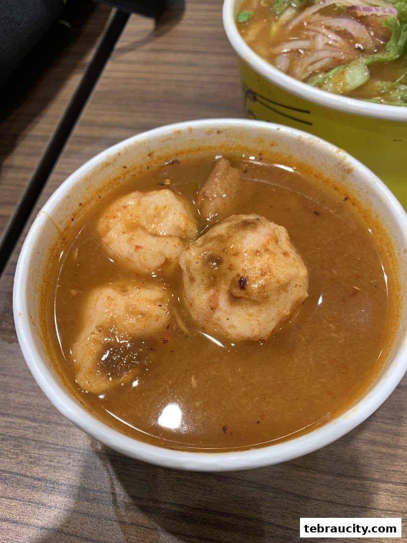 A close-up of a bowl of Laksa with shrimp and other ingredients.
