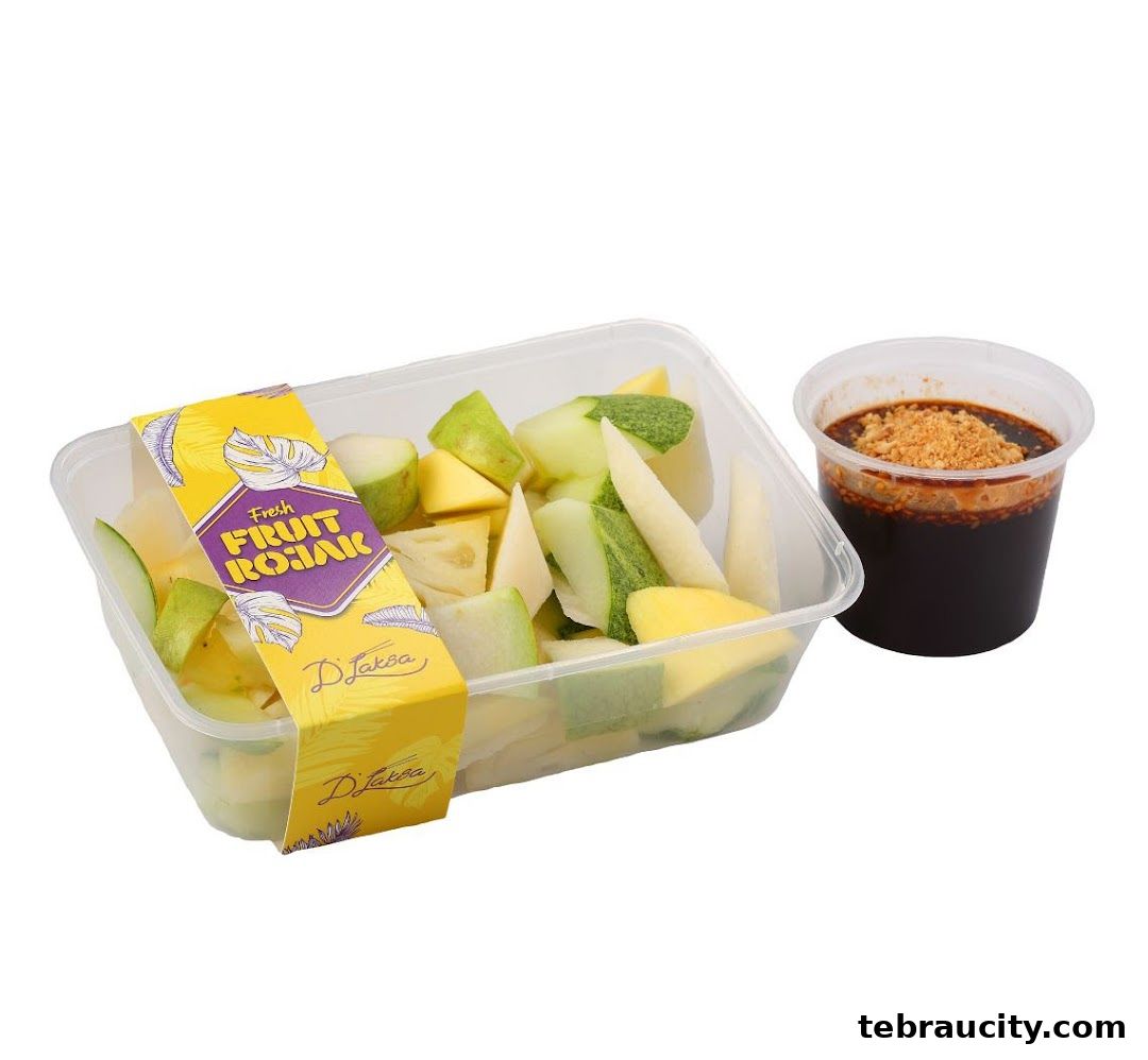 A container of fresh fruit rojak with a side of dipping sauce.