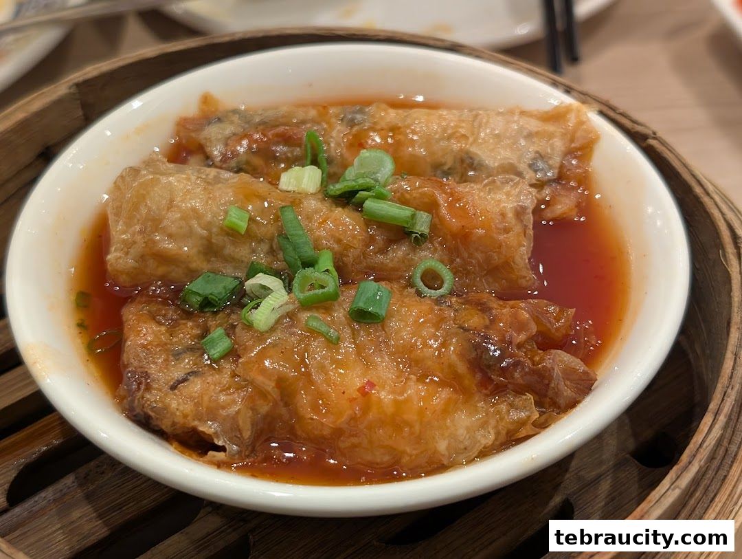 A close-up shot of delicious dim sum, featuring bean curd rolls in a savory sauce.