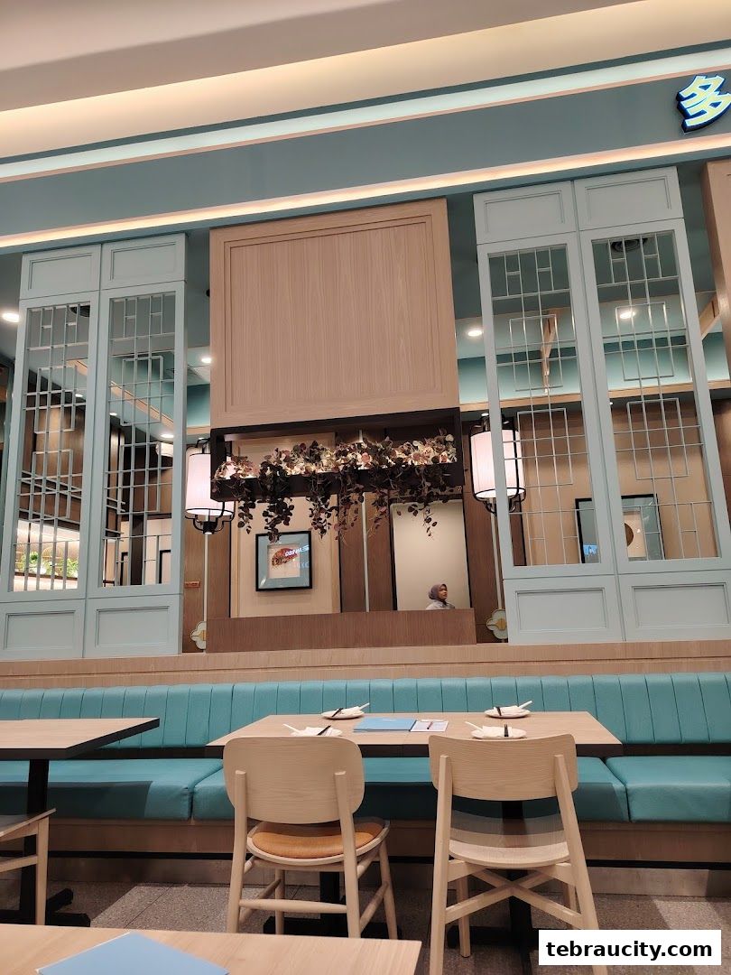 Interior of a modern restaurant with teal banquette seating and light wood chairs.