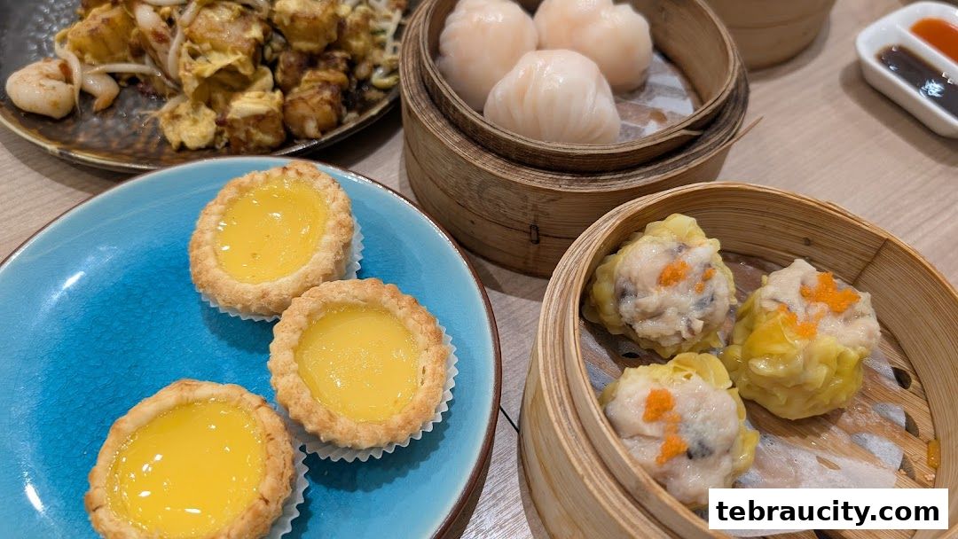 A close-up of various dim sum dishes, including egg tarts and steamed dumplings.
