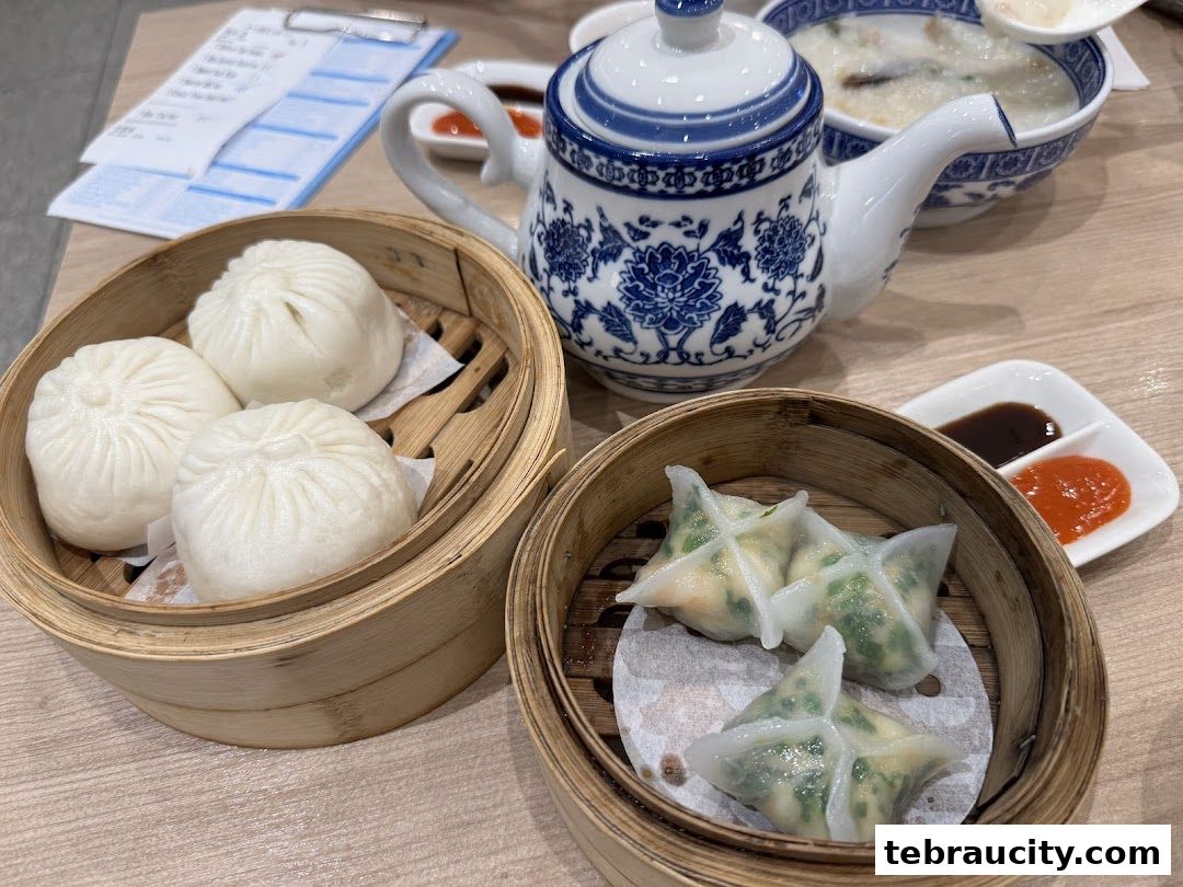 A close-up of delicious dim sum dishes, including steamed buns and dumplings, served with dipping sauces.