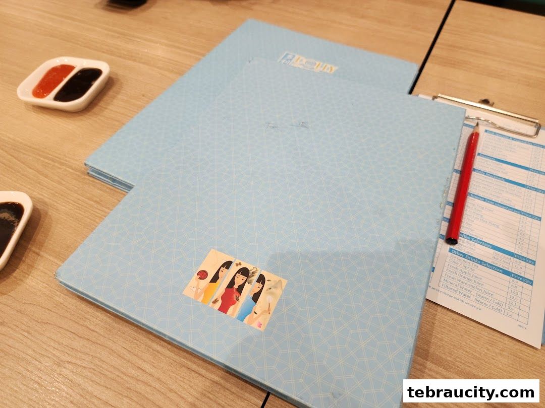 A light blue menu with a geometric pattern and a sticker of four women, next to dipping sauces.