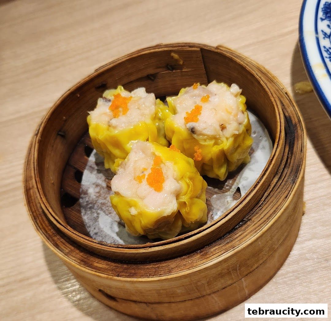A close-up shot of three delicious dim sum dumplings in a bamboo steamer.