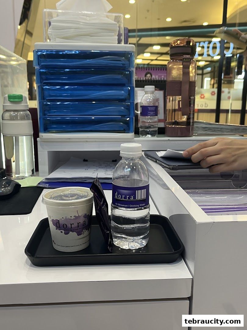 A tray with a cup of drink, a packet, and a bottle of Dorra drinking water.