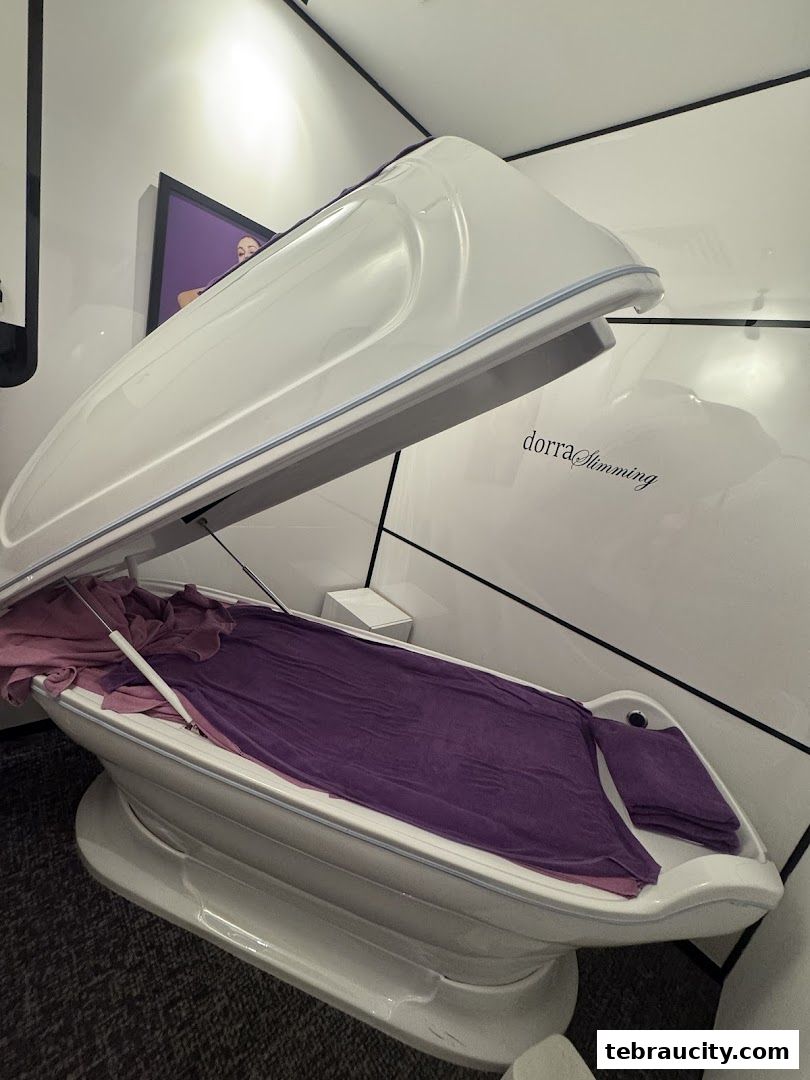 A white slimming pod with purple towels inside, in a clean, modern room.