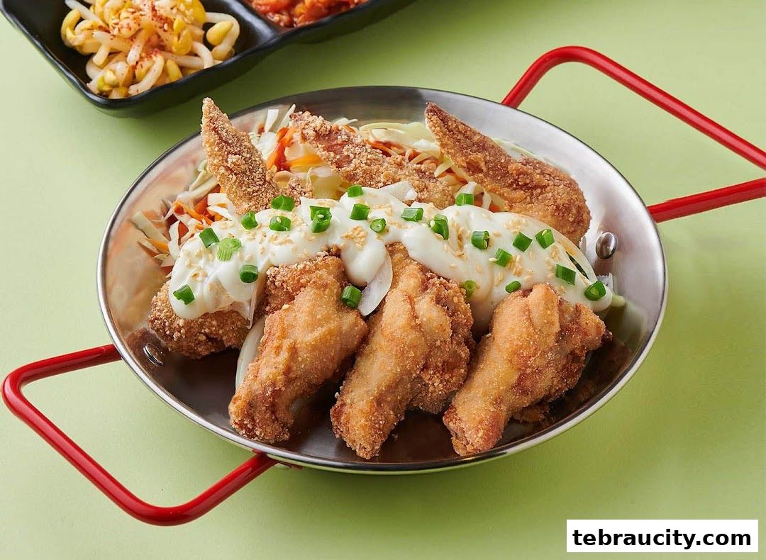 Crispy fried chicken wings served with a creamy sauce and shredded vegetables.
