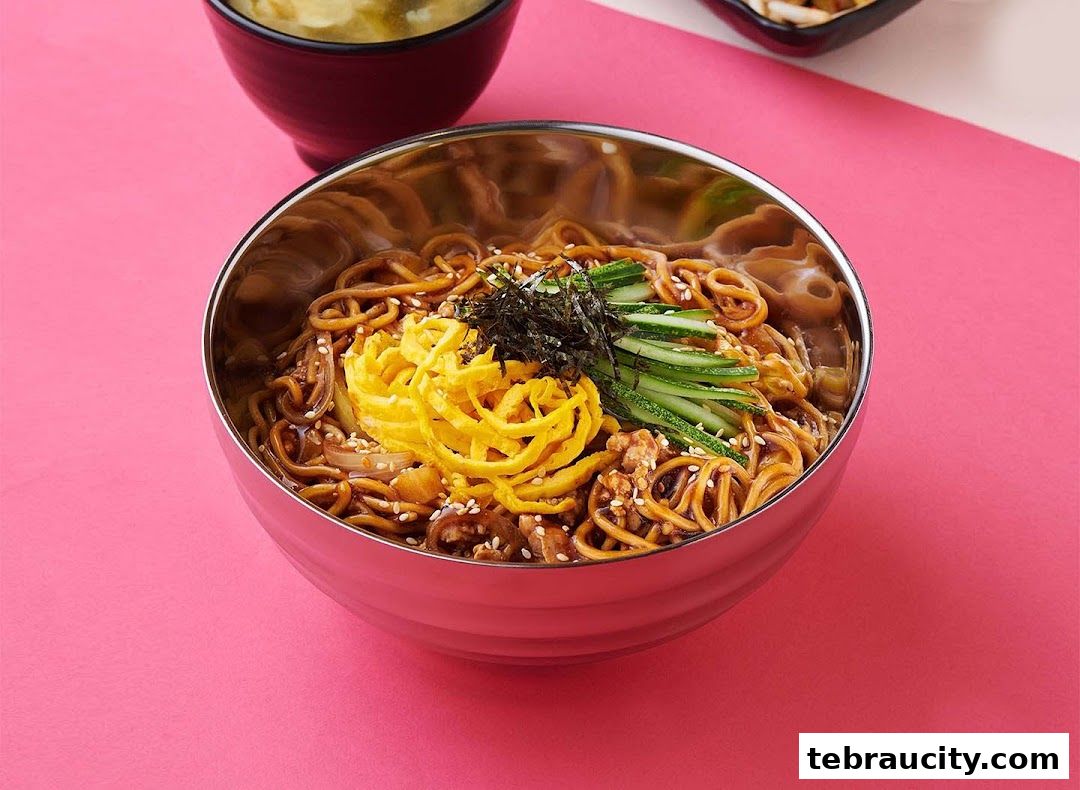 A close-up shot of a delicious Korean noodle dish with shredded egg, cucumber, and seaweed.