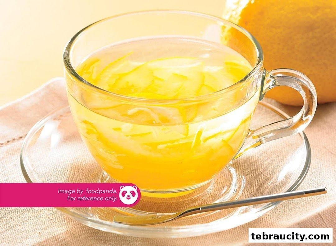 A refreshing glass of lemon tea with fresh lemon slices and a spoon.