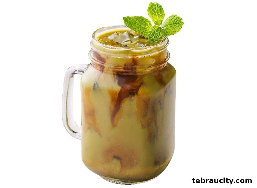 A refreshing iced matcha latte with caramel drizzle and mint garnish in a mason jar.