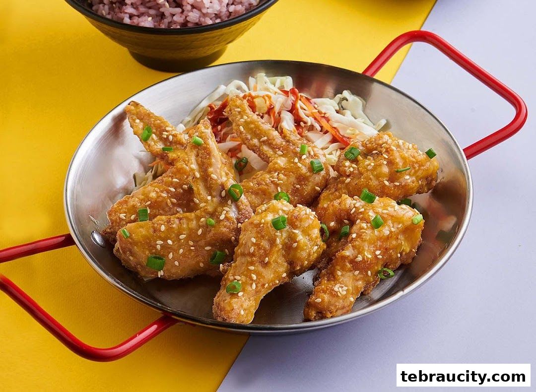 A close-up shot of crispy fried chicken wings with sesame seeds and green onions.