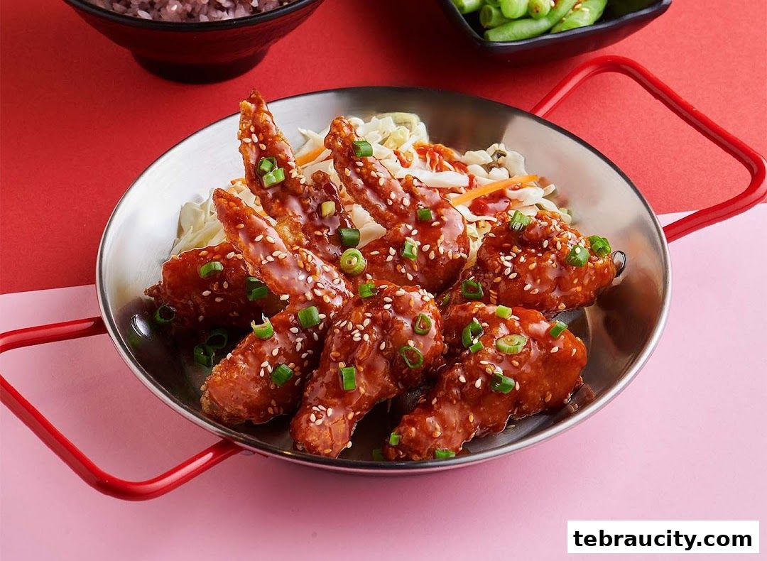 A close-up shot of delicious Korean fried chicken wings glazed with sauce and sprinkled with sesame seeds and green onions.