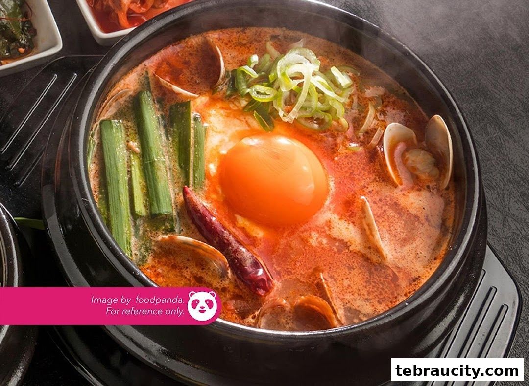 A steaming bowl of Korean soft tofu stew with a raw egg yolk and clams.