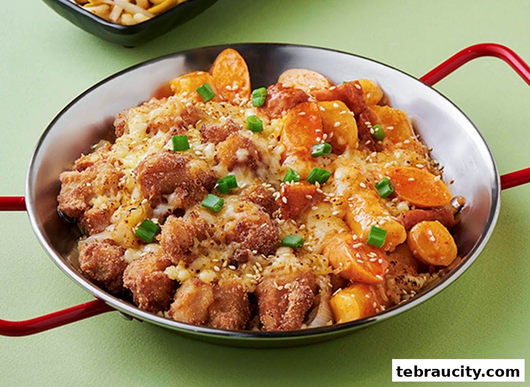 A close-up of a delicious Korean dish with fried chicken, tteokbokki, and melted cheese.
