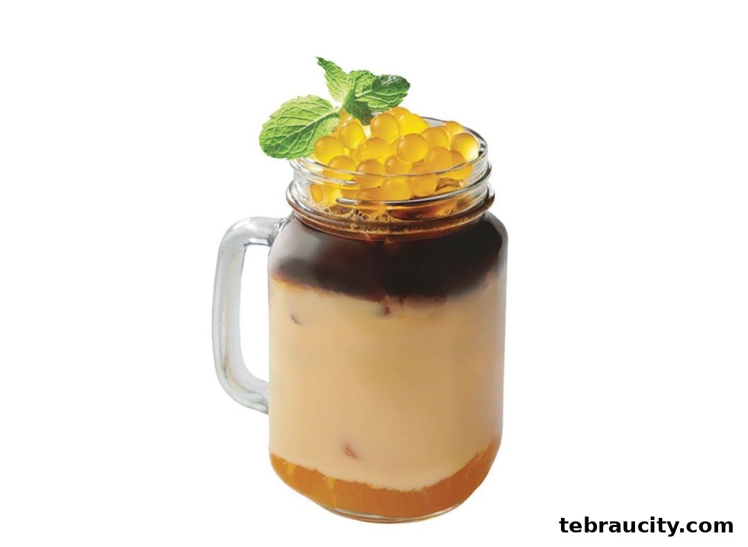 A layered beverage in a mason jar with pearls and mint leaves.