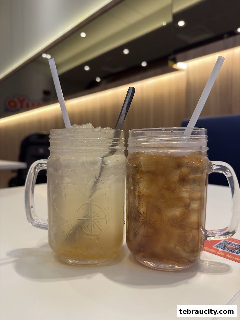 Two refreshing drinks in mason jars with straws on a white table.