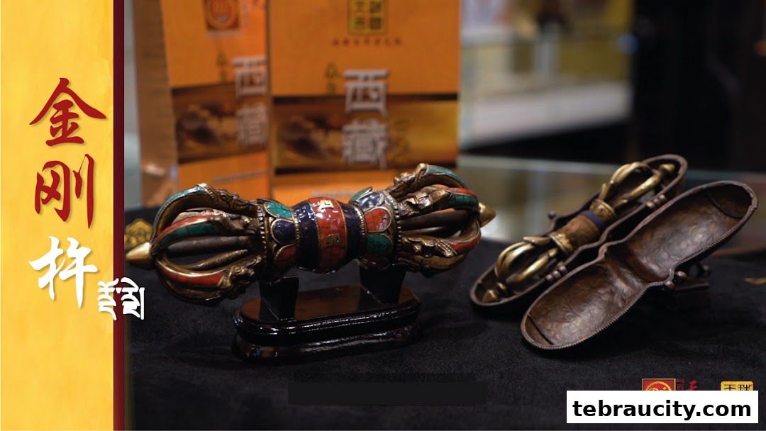 Close-up of ornate Tibetan ritual objects, a vajra and a dorje, displayed on a black cloth.