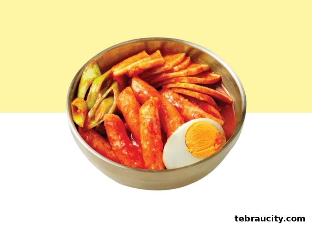 A bowl of Korean Tteokbokki with a boiled egg and scallions.