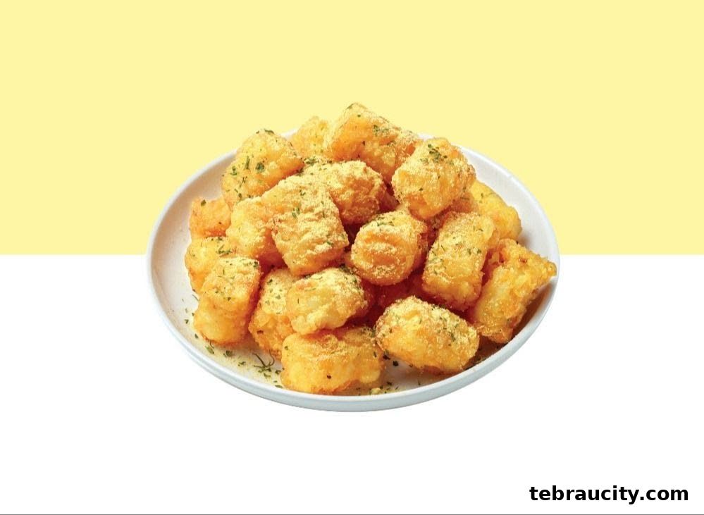 A white bowl filled with golden-brown, crispy potato tots sprinkled with cheese powder and parsley.