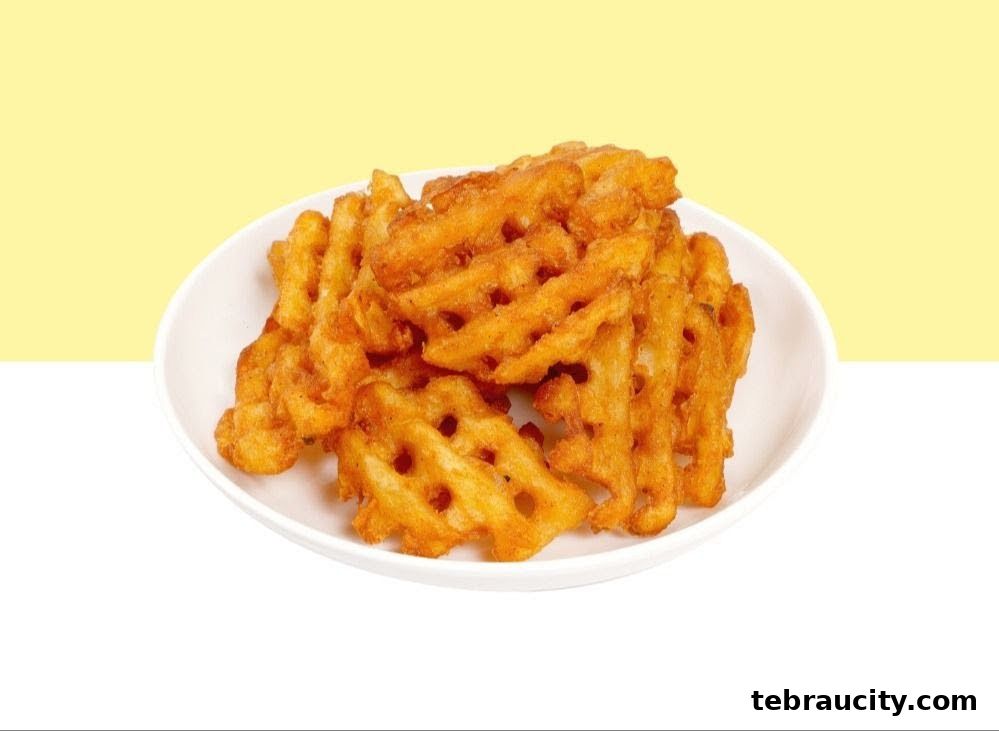 A white plate filled with golden-brown waffle fries against a yellow and white background.