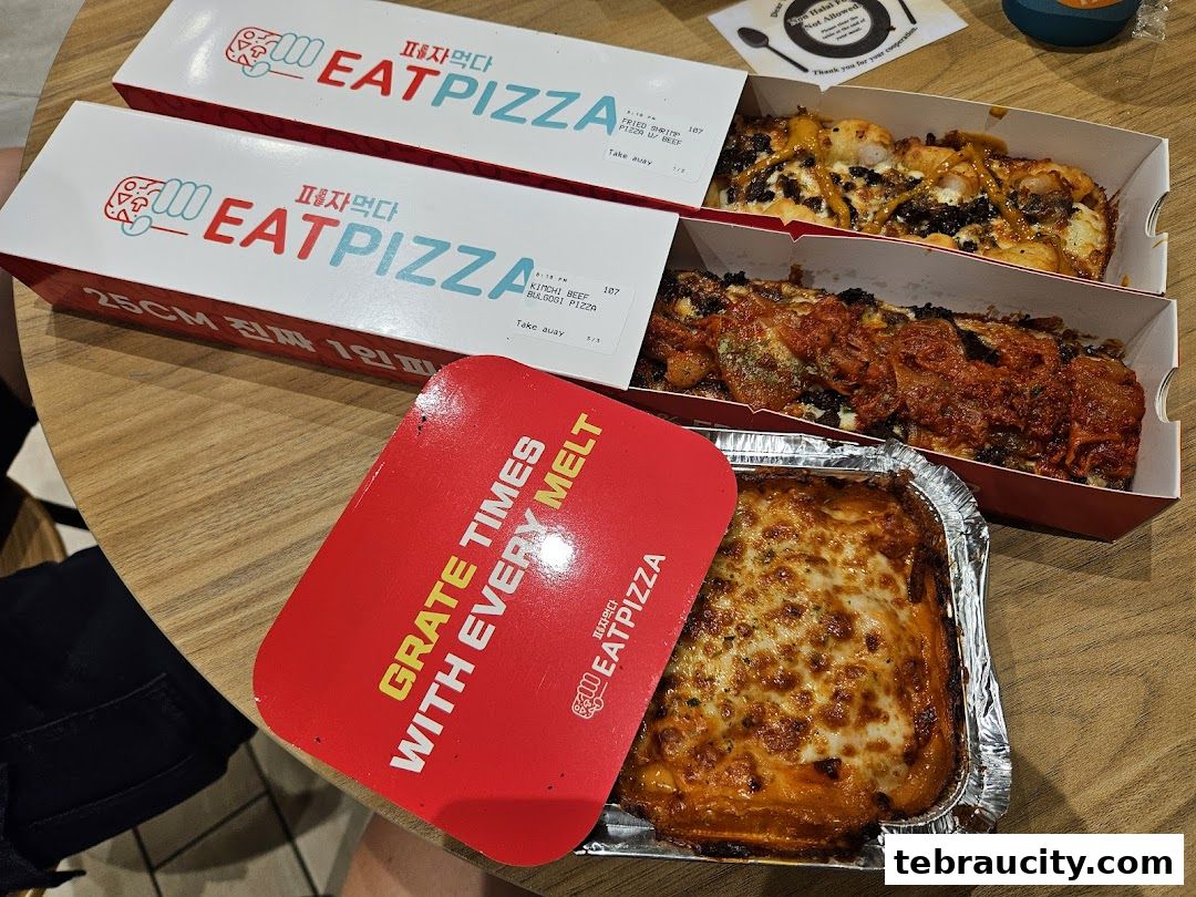 A table with pizza boxes and a baked dish from Eat Pizza.