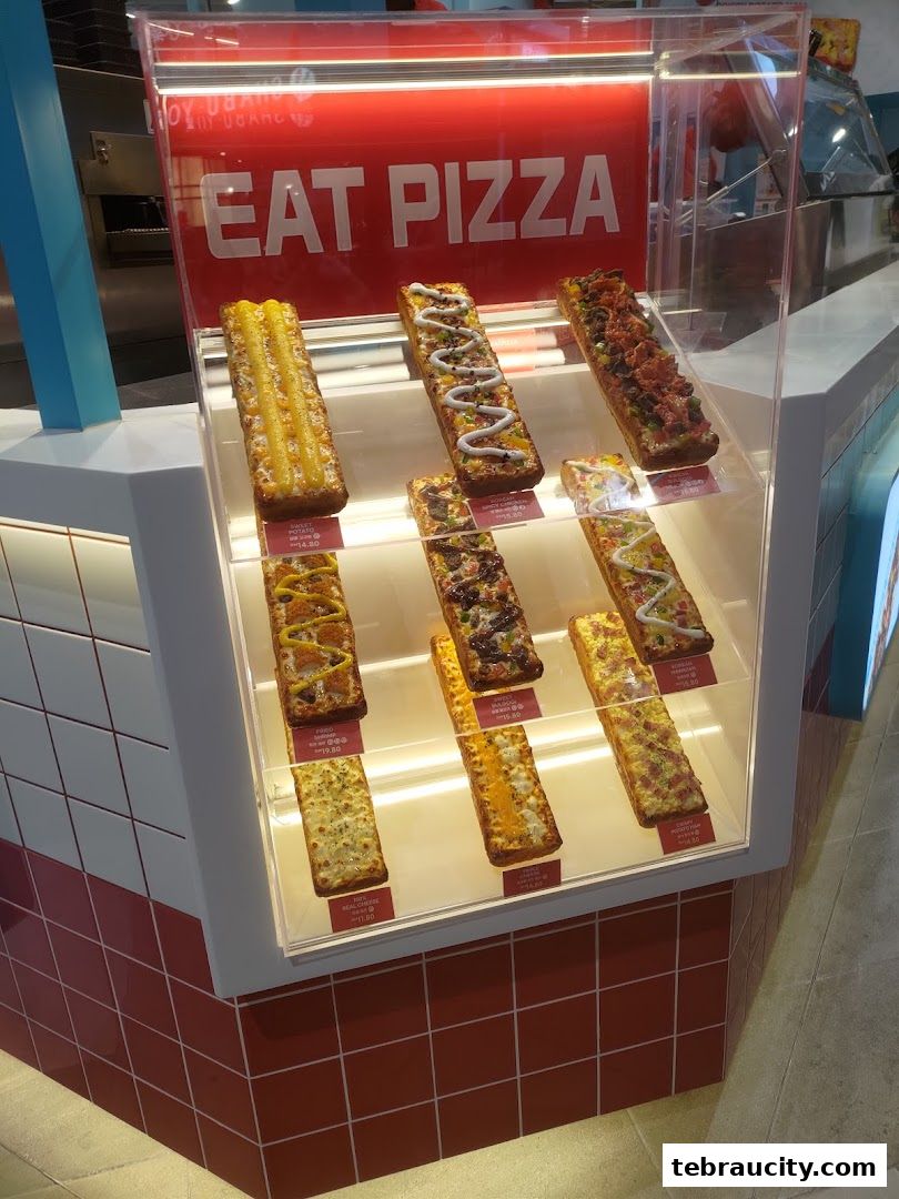 A display case filled with various rectangular pizzas with different toppings.