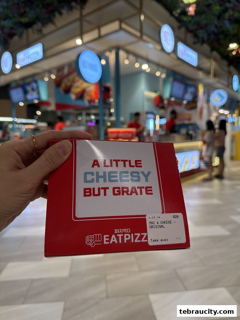 A hand holds a red pizza box with "Eat Pizza" branding and a cheesy slogan.